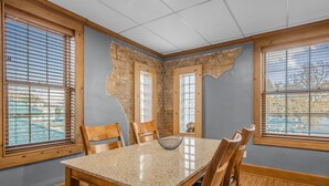 Un comedor con una mesa de granito, sillas de madera y vistas amplias por las ventanas.