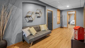 Una sala de estar moderna con un sofá gris, piso de madera y un extintor.