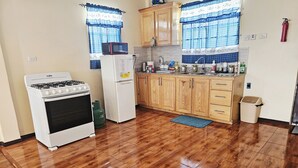 Una cocina con estufa a gas, refrigerador, muebles de madera y piso de baldosas.