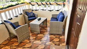 Un patio con mobiliario de mimbre, suelo de piedra y un letrero que dice 'Home Sweet Home'.