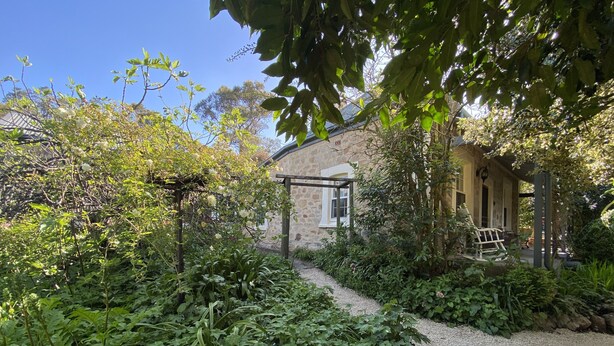 Une maison en pierre avec un chemin de gravier menant à un porche en bois.