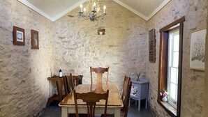 Une salle à manger rustique avec un mur en pierre, une table à manger en bois, des chaises et un lustre.