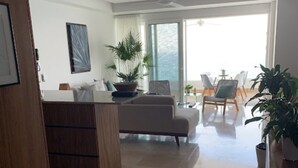 Un salon moderne comprenant un canapé, une table basse et un coin repas avec des chaises.