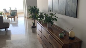 Un salon moderne avec une console en bois, des plantes en pot et un grand tableau abstrait accroché au mur.