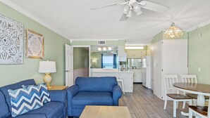 Ein Wohnzimmer mit einem blauen Sofa, einem Holztisch und einem Essbereich mit weißen Stühlen und einem Holztisch.