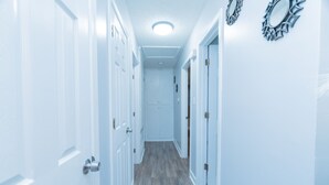 A narrow hallway with white doors and a wooden floor.