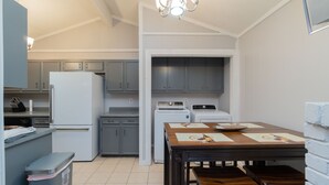 A compact kitchen with a refrigerator, stove, and cabinets. There is a dining table with benches.