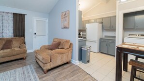 A living room with two sofas, a dining table, and a kitchen area with cabinets and appliances.