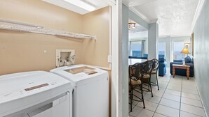 A laundry area with two white washing machines, a drying rack, and a small cabinet. - The Summit PCB 1504 ** Large Updated Condo with Huge Beachfront Balcony (Panama City Beach)