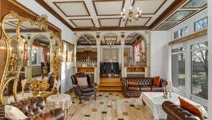 Een weelderige woonkamer met sierlijk meubilair, een grote spiegel en een kroonluchter.
