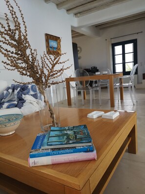 Ein Holztisch mit einer Vase gefüllt mit getrockneten Ästen, einer Schüssel und einem Stapel Bücher.
