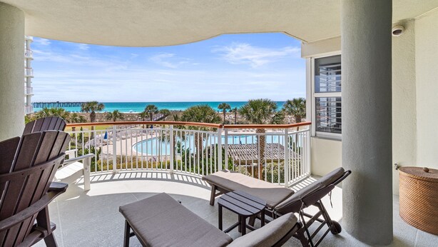 Ein Balkon mit Liegestühlen und Blick auf Pool und Meer.