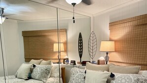 Une chambre d’hôtel avec un grand lit, deux tables de chevet, un ventilateur de plafond et un miroir.
