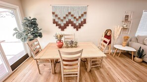 Un coin repas avec une table en bois, des chaises et une décoration murale en macramé.