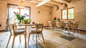 A wooden interior with a dining area, chairs, a table, and hanging lights. - Cozy apartment in KLECINO with lake view (KLECINO)