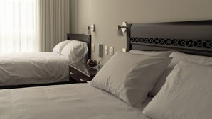 Una habitación de hotel con dos camas, una mesita de noche con lámpara y un teléfono.