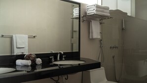 Un baño moderno con encimera negra, un lavabo, un espejo y una ducha con mampara de vidrio.