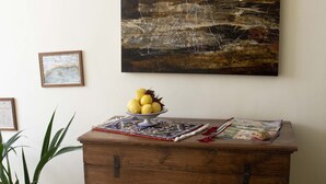 Een houten kast met een schaal citroenen erop, een kamerplant en een schilderij aan de muur.