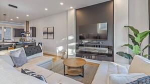 A modern living room with a sofa, coffee table, and a TV mounted on a wall. - 2mi to DT, 4 Private Rooms, Roof Deck Amazing View (Nashville)