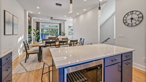 A modern kitchen with a central island, pendant lights, and a large wall clock. - 2mi to DT, 4 Private Rooms, Roof Deck Amazing View (Nashville)