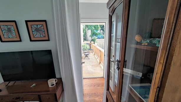 Une pièce avec un bureau en bois, une armoire et une vue sur une terrasse extérieure.