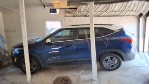 Un SUV azul estacionado en un garaje con pisos de concreto y paredes blancas.