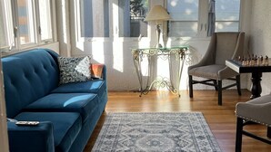 Un salon chaleureux avec un canapé bleu, une table d’échecs et un tapis à motifs.