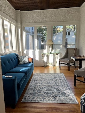 Ein gemütliches Wohnzimmer mit einem blauen Sofa, einem Schachtisch und einem gemusterten Teppich.