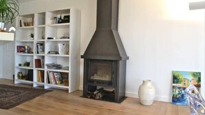 A living room with a fireplace, white shelving units, a rug, and a painting. - Villa Roccu (Borgo)