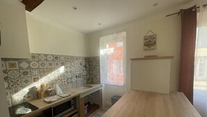 A kitchen with patterned tiles, a wooden table, and a window with a curtain.