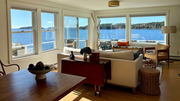 Ein geräumiges Wohnzimmer mit großen Fenstern und Blick auf das Meer.