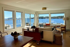 A spacious living room with large windows offering a view of the sea.