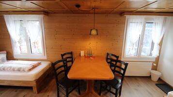 A wooden-paneled room with a bed, a table with chairs, and a hanging light fixture.