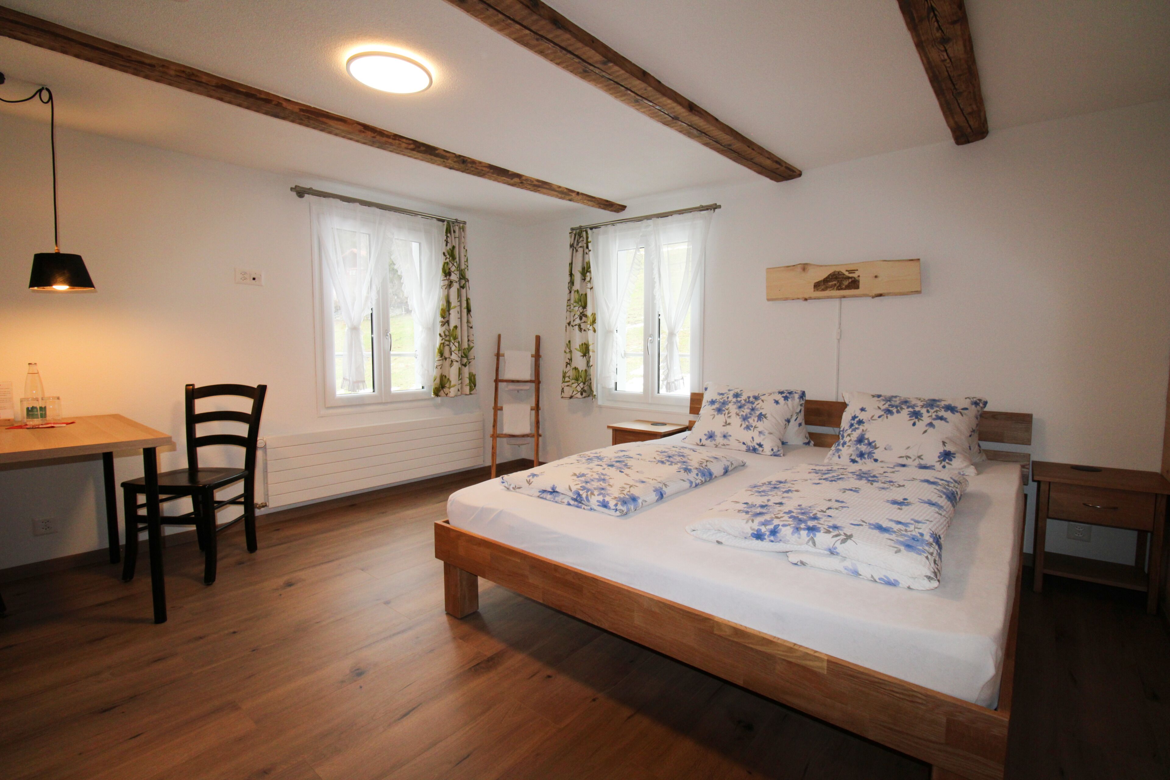 A bedroom with a wooden bed, a desk, and a chair.