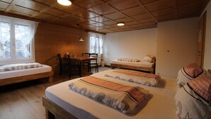 A cozy room with a wooden ceiling, a bed with patterned bedding, a small table, and a window with curtains. - Gasthaus Schwand (Engelberg)