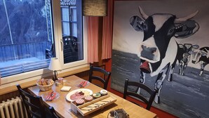 A dining table with plates of food, a painting of a cow, and chairs. - Gasthaus Schwand (Engelberg)