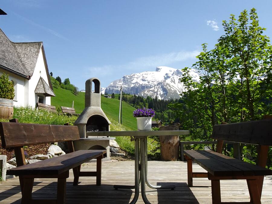 Una terraza de madera con bancos, una mesa de piedra y una maceta.