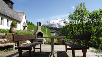 A wooden deck with benches, a stone table, and a flower pot.