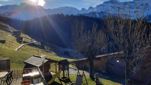 A mountain landscape with a wooden play structure and a small building with a sloped roof. - Gasthaus Schwand (Engelberg)
