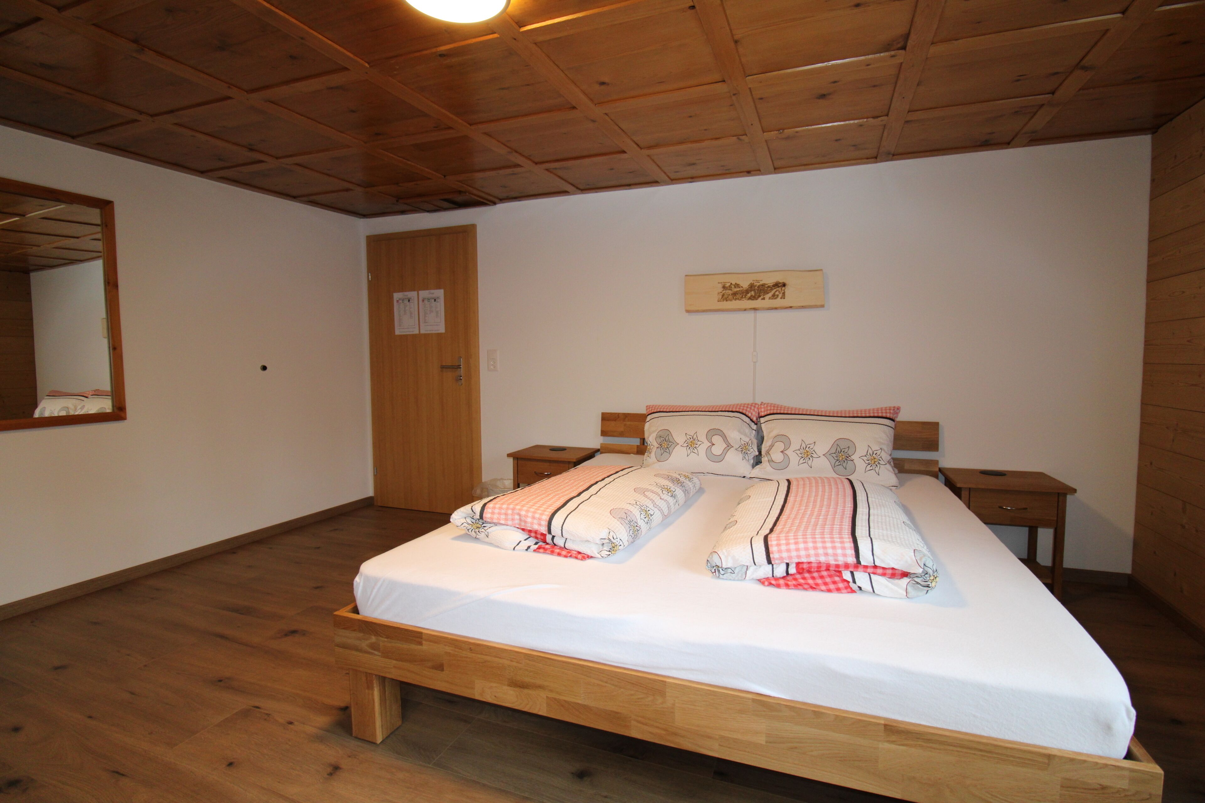 Un dormitorio con cama, mesita de noche, cómoda y techo de madera.
