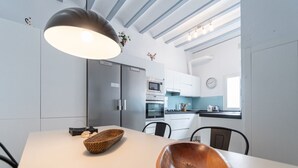 A modern kitchen with white cabinets, a large island, and a hanging light fixture. - Apartament Sweet Home in Cádiz (Cádiz)