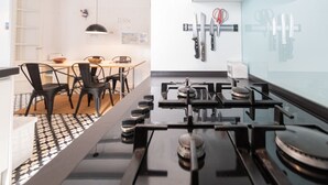A modern kitchen with a gas stove, black chairs, and a dining table. - Apartament Sweet Home in Cádiz (Cádiz)