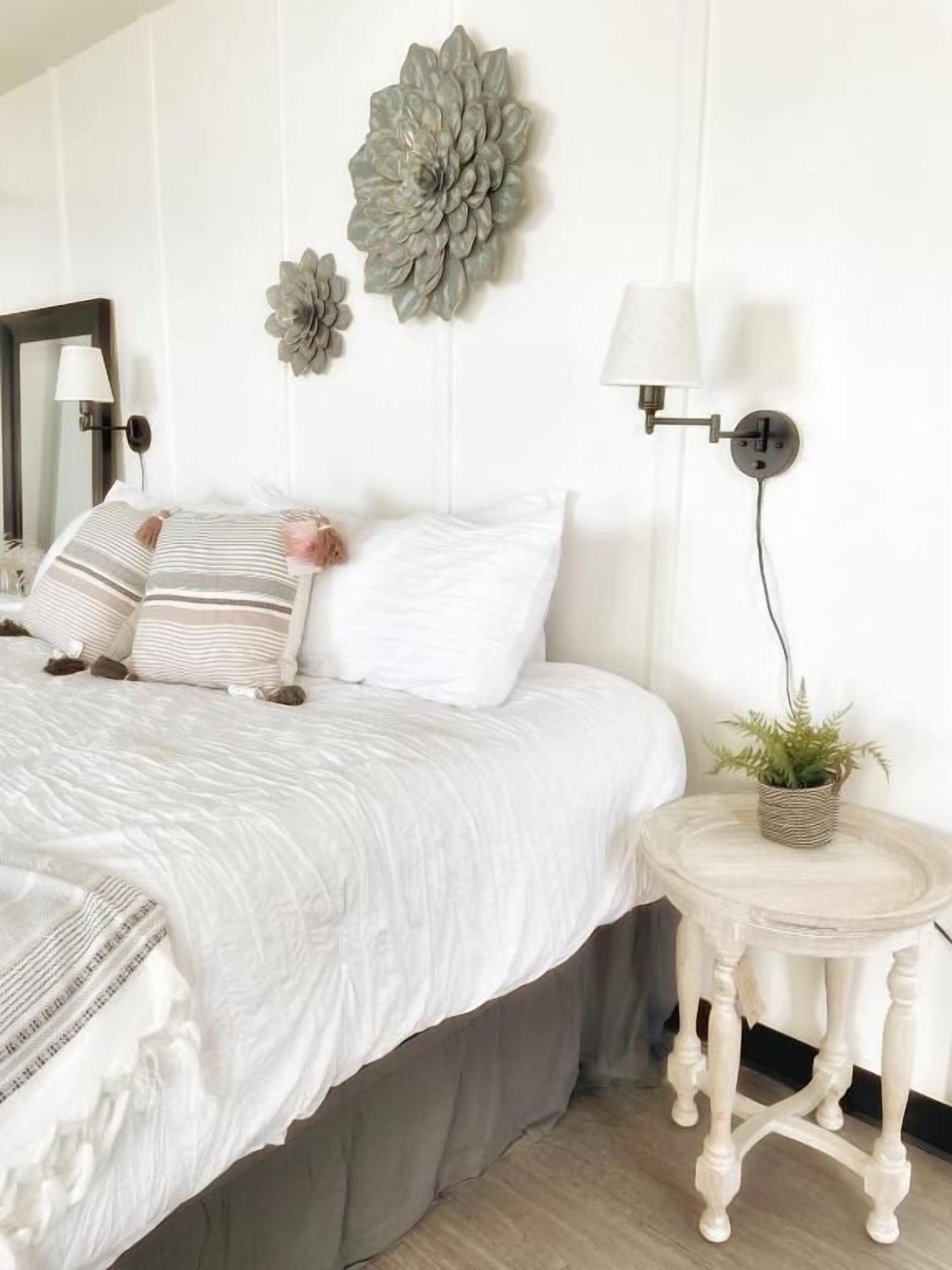 A bedroom with a large bed, a bedside table with a lamp, and decorative wall art.