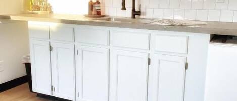 Una cocina con armarios blancos, encimera de madera y salpicadero.