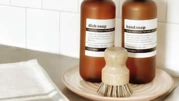 Two bottles of dish soap and hand soap on a plate with a brush.