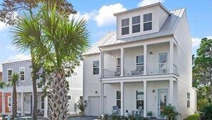 A two-story residential building with a balcony on the second floor, a front porch with outdoor seating, and a well-maintained lawn. - Beautiful 30A Beach House - short walk to beach! (Santa Rosa Beach)