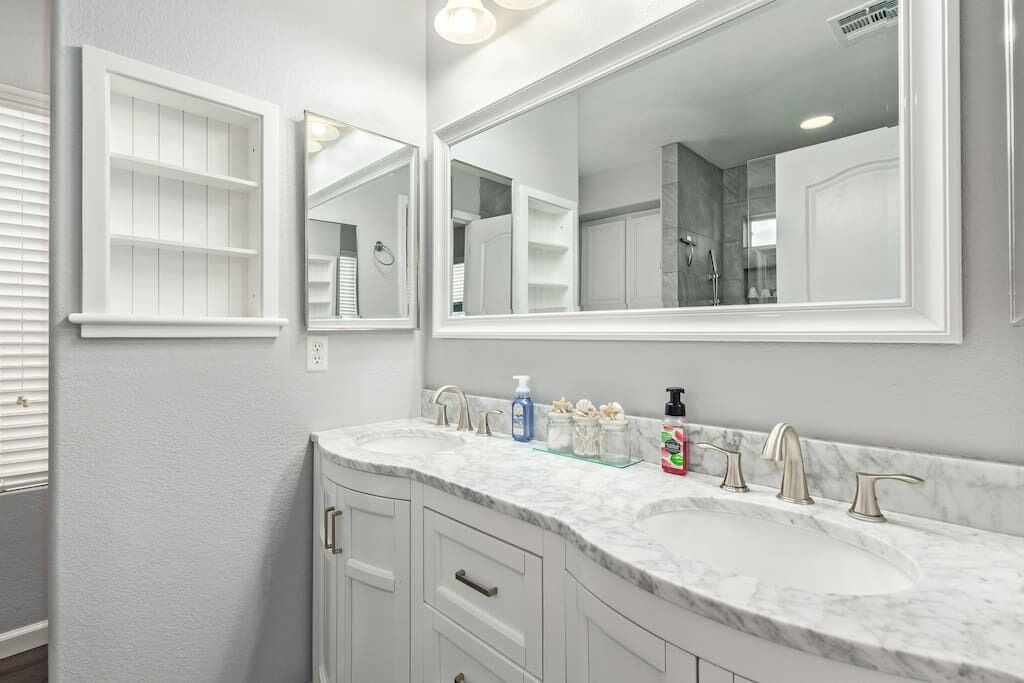 A bathroom with two sinks, a large mirror, and a vanity with drawers.