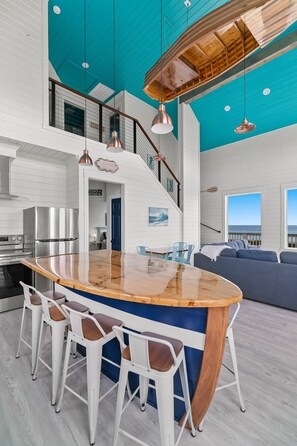 A modern kitchen with a large island, bar stools, and a view of the ocean.