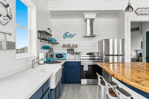 A modern kitchen with white cabinetry, a wooden island, stainless steel appliances, and a view of the city.