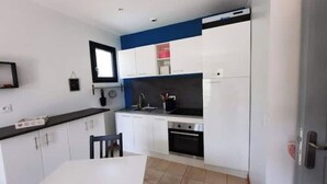 Cozinha moderna com armários brancos, bancada preta e forno embutido.